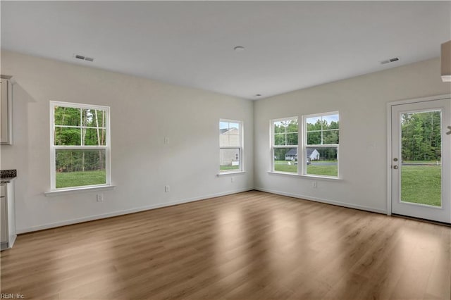 empty room featuring visible vents, baseboards, and light wood-style floors