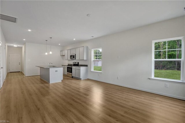 kitchen with stainless steel electric range oven, visible vents, open floor plan, and an island with sink