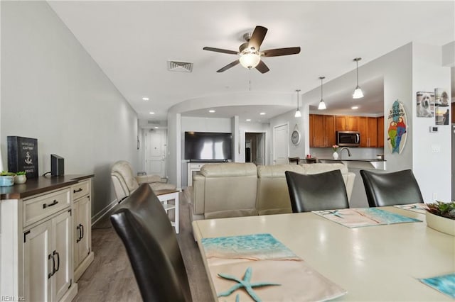 dining space featuring ceiling fan, light wood-type flooring, and sink