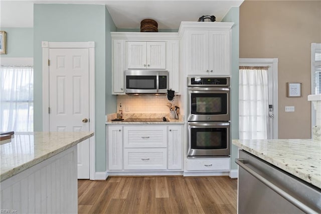 kitchen with stainless steel appliances, plenty of natural light, light hardwood / wood-style floors, and white cabinetry