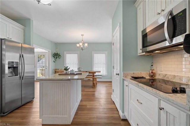 kitchen featuring white cabinets, pendant lighting, a kitchen island, light hardwood / wood-style flooring, and appliances with stainless steel finishes