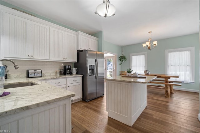 kitchen featuring a healthy amount of sunlight, hanging light fixtures, stainless steel refrigerator with ice dispenser, and white cabinetry