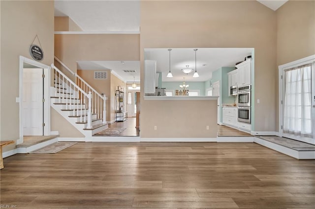 unfurnished living room with a high ceiling, hardwood / wood-style floors, and a notable chandelier