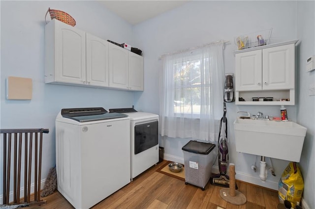 washroom featuring light hardwood / wood-style floors, washer and dryer, cabinets, and sink