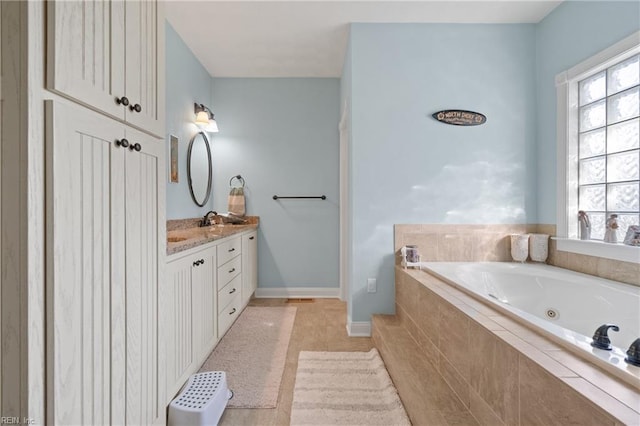 bathroom featuring tile patterned floors, a relaxing tiled tub, and vanity