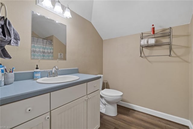 bathroom with vaulted ceiling, hardwood / wood-style floors, vanity, and toilet