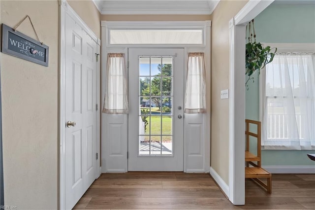 doorway with light wood-type flooring, crown molding, and plenty of natural light