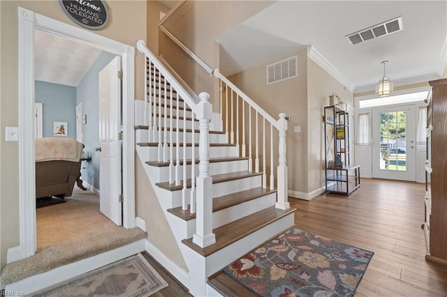 foyer featuring hardwood / wood-style flooring, crown molding, and vaulted ceiling