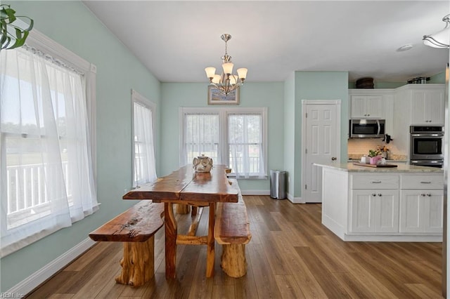 dining space with an inviting chandelier and light hardwood / wood-style flooring