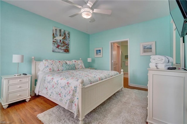 bedroom with connected bathroom, light wood-type flooring, and ceiling fan