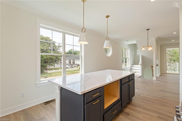 kitchen with light hardwood / wood-style flooring, a center island, light stone countertops, and a wealth of natural light