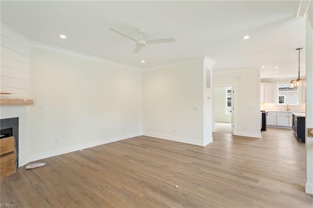 unfurnished living room featuring light hardwood / wood-style flooring, ceiling fan, a tiled fireplace, and crown molding