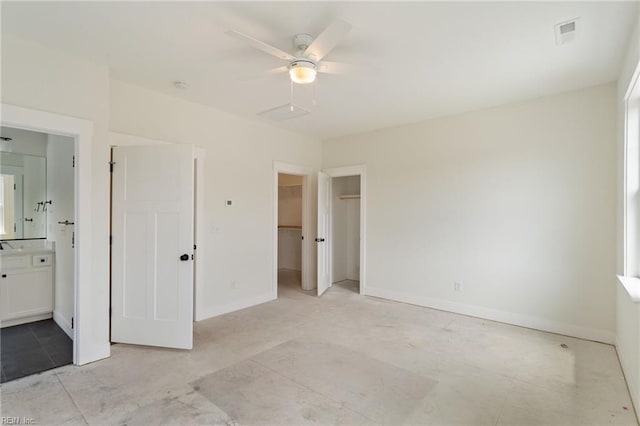 unfurnished bedroom with a closet, a spacious closet, connected bathroom, and ceiling fan