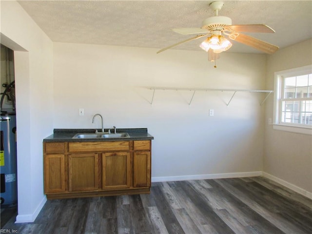 interior space featuring electric water heater, ceiling fan, sink, dark hardwood / wood-style floors, and a textured ceiling