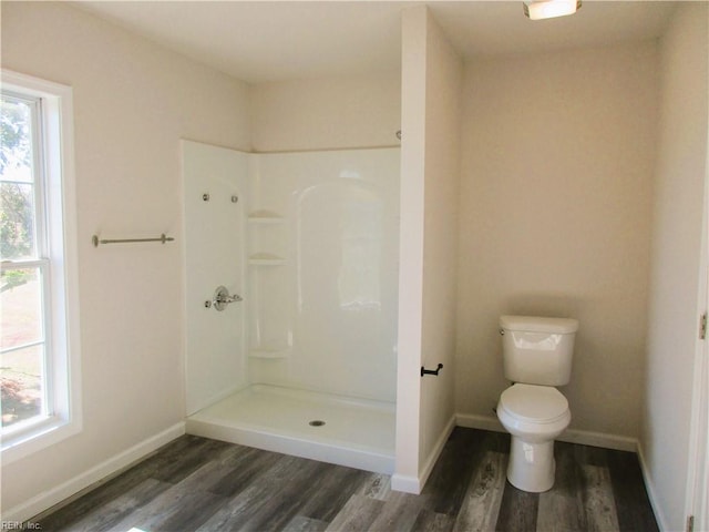 bathroom with wood-type flooring, toilet, and a shower