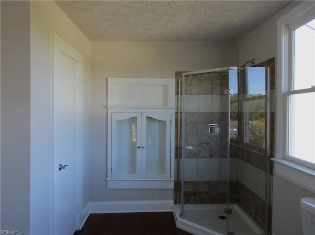 bathroom with walk in shower, a textured ceiling, toilet, and a wealth of natural light