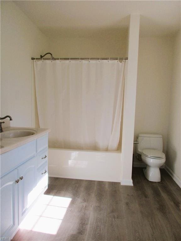 full bathroom featuring hardwood / wood-style floors, shower / bath combination with curtain, toilet, and vanity