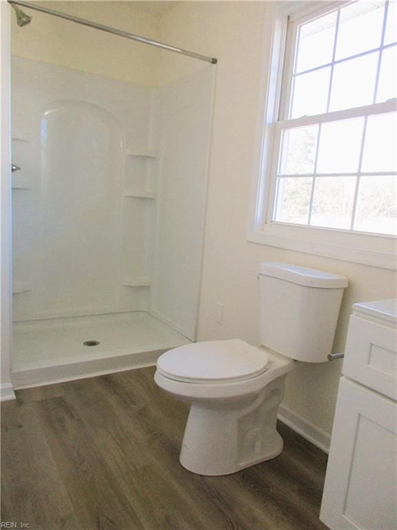 bathroom featuring walk in shower, hardwood / wood-style flooring, a wealth of natural light, and toilet