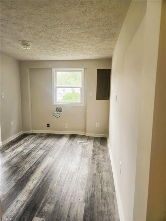 unfurnished room featuring electric panel, hardwood / wood-style flooring, and a textured ceiling