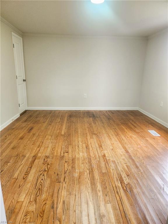 unfurnished room featuring hardwood / wood-style flooring and crown molding