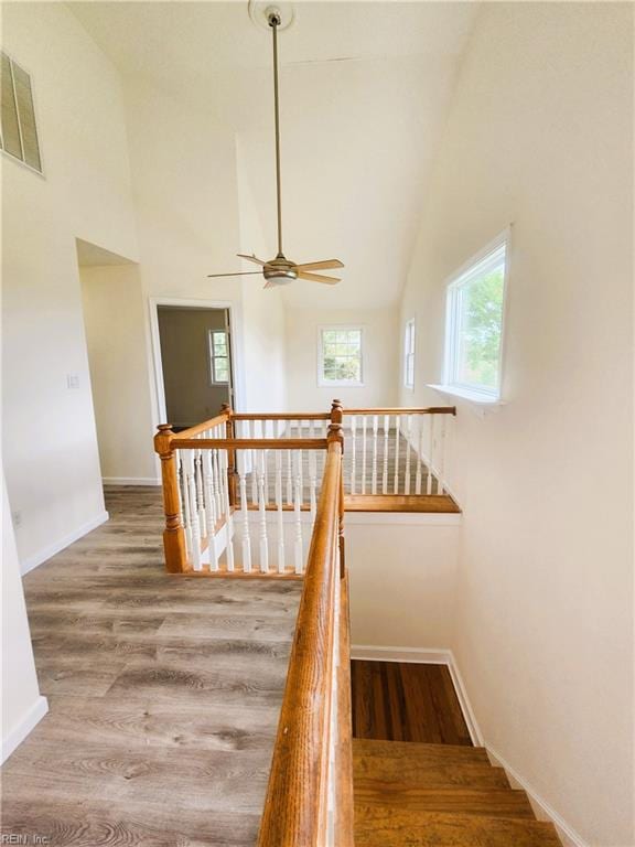 staircase featuring wood-type flooring, high vaulted ceiling, and ceiling fan