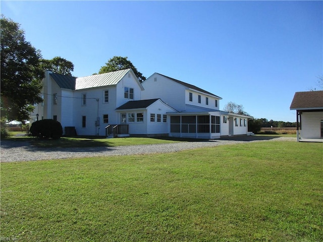 rear view of house with a sunroom and a lawn