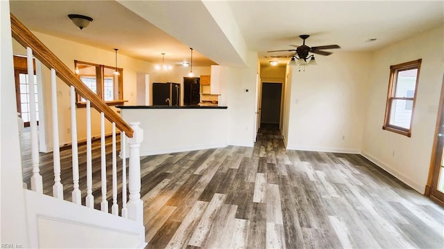 unfurnished living room with wood-type flooring and ceiling fan with notable chandelier