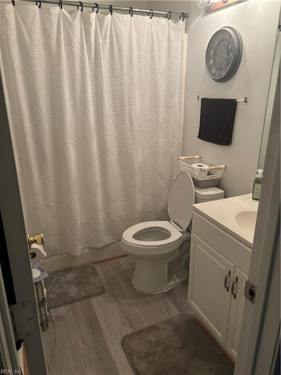 full bathroom with shower / tub combo with curtain, hardwood / wood-style floors, vanity, and toilet