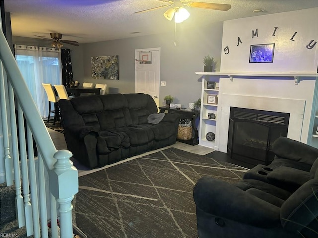 living room with ceiling fan, dark hardwood / wood-style flooring, and a textured ceiling