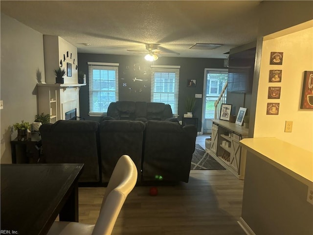 living room with ceiling fan, dark hardwood / wood-style flooring, and a textured ceiling