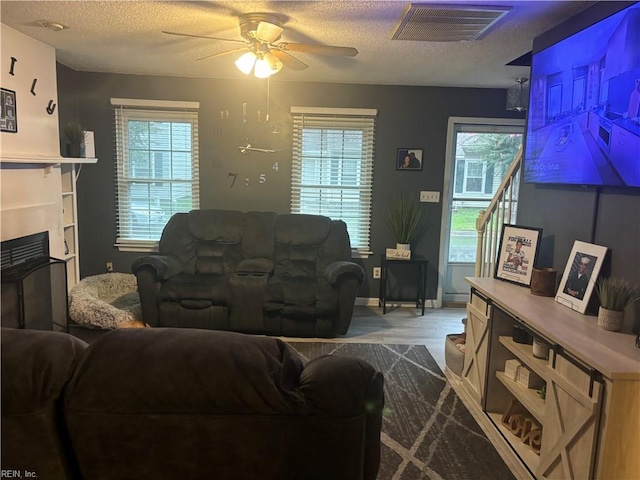 living room with a healthy amount of sunlight, ceiling fan, light hardwood / wood-style flooring, and a textured ceiling