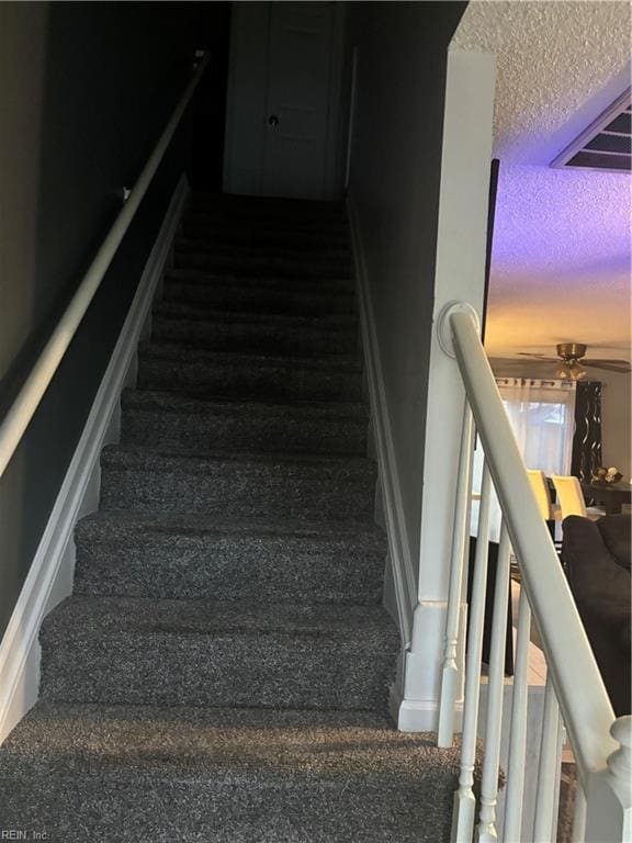 stairway with ceiling fan and carpet