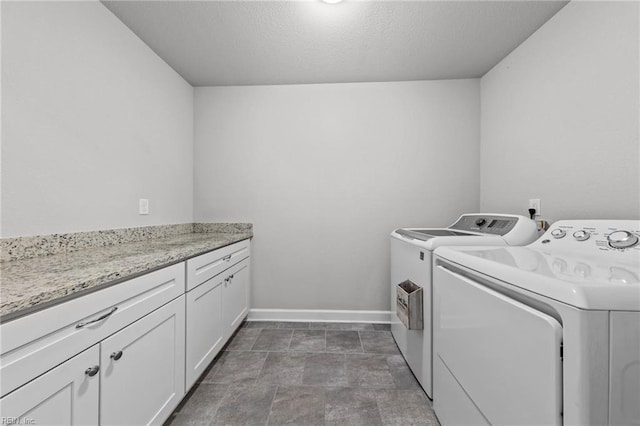 washroom featuring cabinets, a textured ceiling, and washing machine and dryer