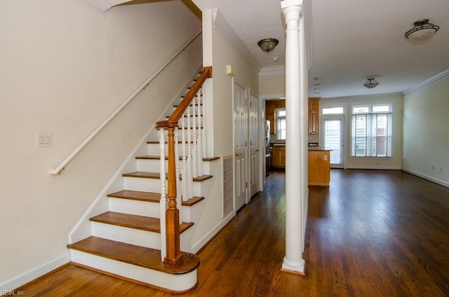 staircase with ornate columns, wood-type flooring, and ornamental molding