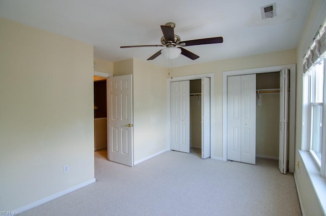 unfurnished bedroom featuring light carpet, multiple windows, and ceiling fan