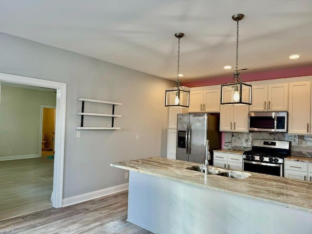 kitchen with hanging light fixtures, backsplash, appliances with stainless steel finishes, white cabinetry, and light stone countertops