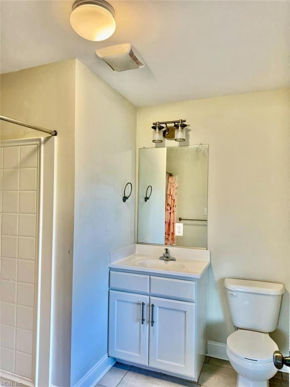 bathroom featuring vanity, toilet, a shower, and tile patterned flooring