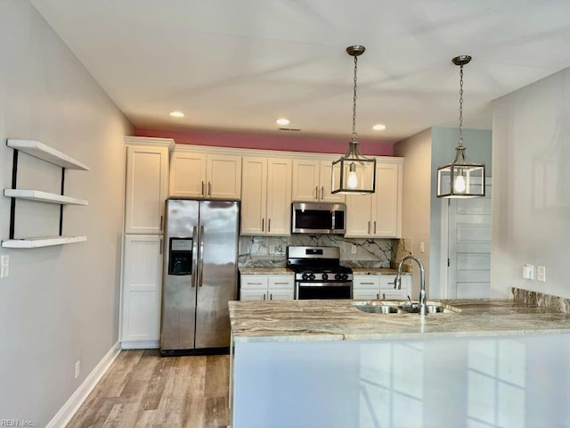 kitchen with hanging light fixtures, kitchen peninsula, sink, white cabinets, and appliances with stainless steel finishes