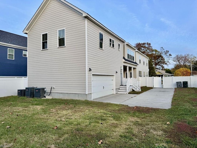 back of house featuring cooling unit, a yard, and a garage