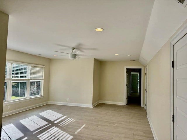 empty room featuring ceiling fan, light wood-type flooring, and vaulted ceiling