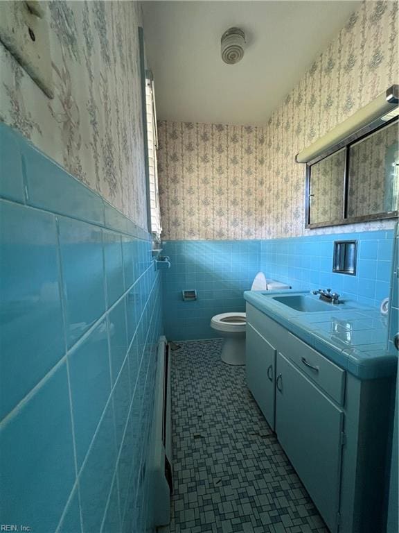 bathroom featuring vanity, tile walls, and toilet