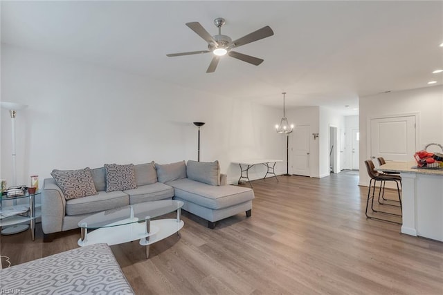 living room featuring wood-type flooring and ceiling fan with notable chandelier