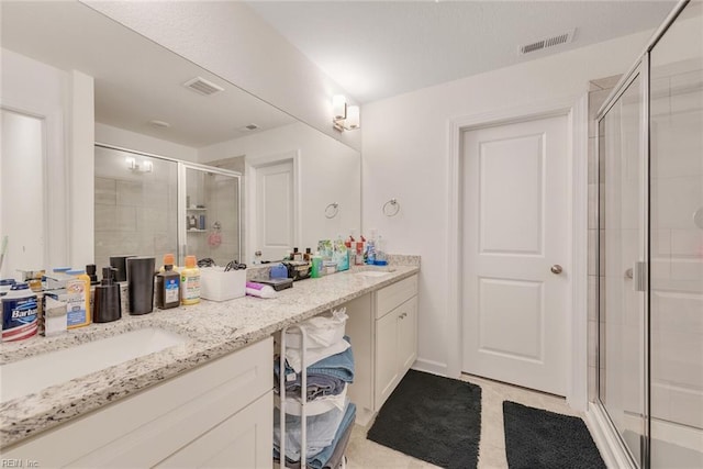 bathroom with a shower with door and vanity