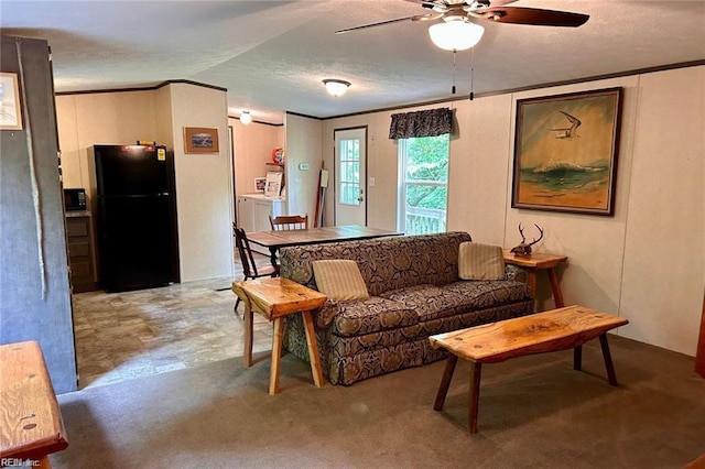 carpeted living room featuring ceiling fan, a textured ceiling, washer and clothes dryer, and ornamental molding