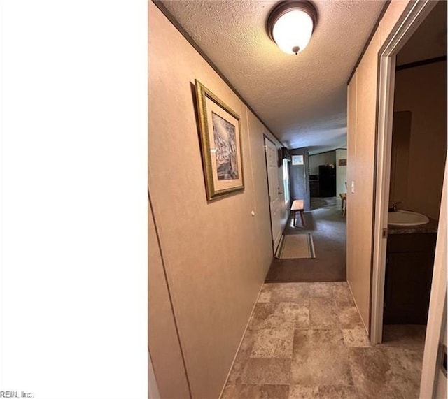 corridor with a textured ceiling and sink