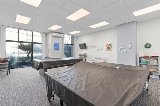 playroom featuring a paneled ceiling, carpet, a wall mounted air conditioner, and floor to ceiling windows