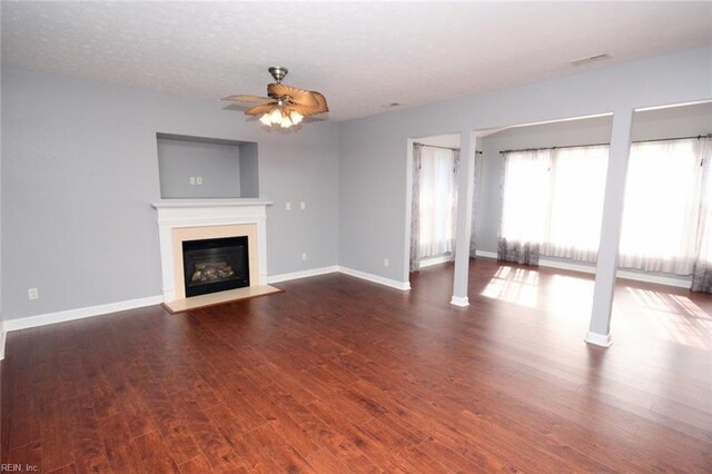 unfurnished living room featuring dark wood-type flooring, a textured ceiling, and ceiling fan