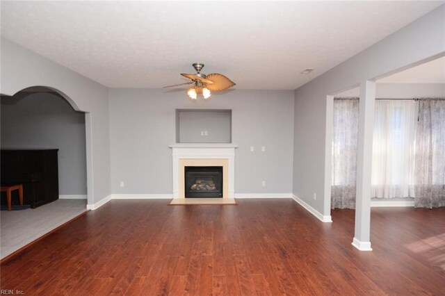 unfurnished living room featuring dark wood-type flooring and ceiling fan