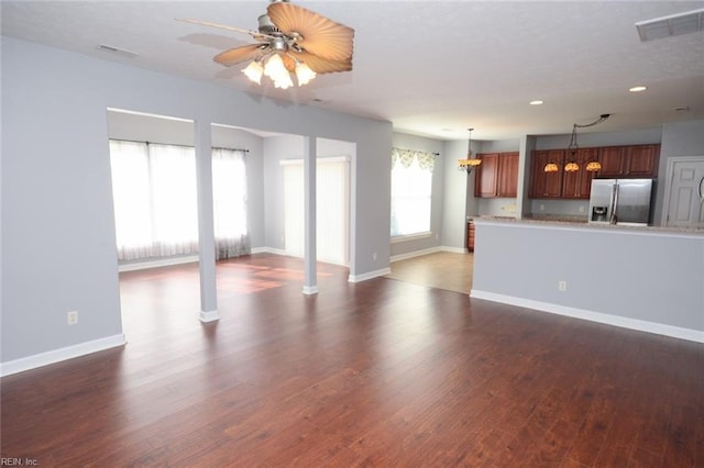 unfurnished living room with dark wood-type flooring and ceiling fan with notable chandelier