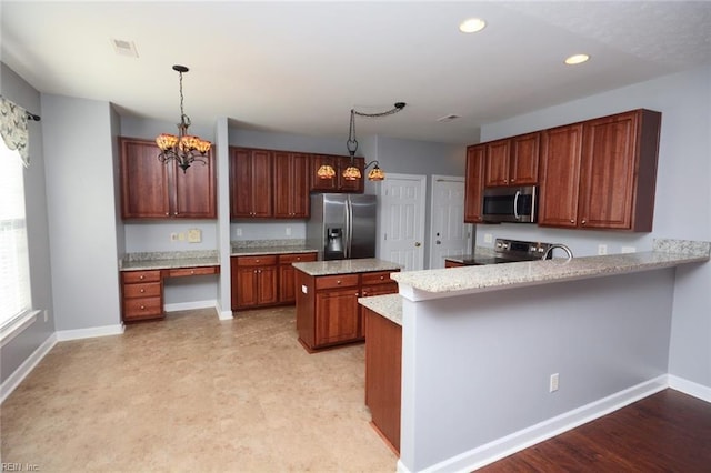 kitchen with built in desk, kitchen peninsula, a notable chandelier, decorative light fixtures, and appliances with stainless steel finishes